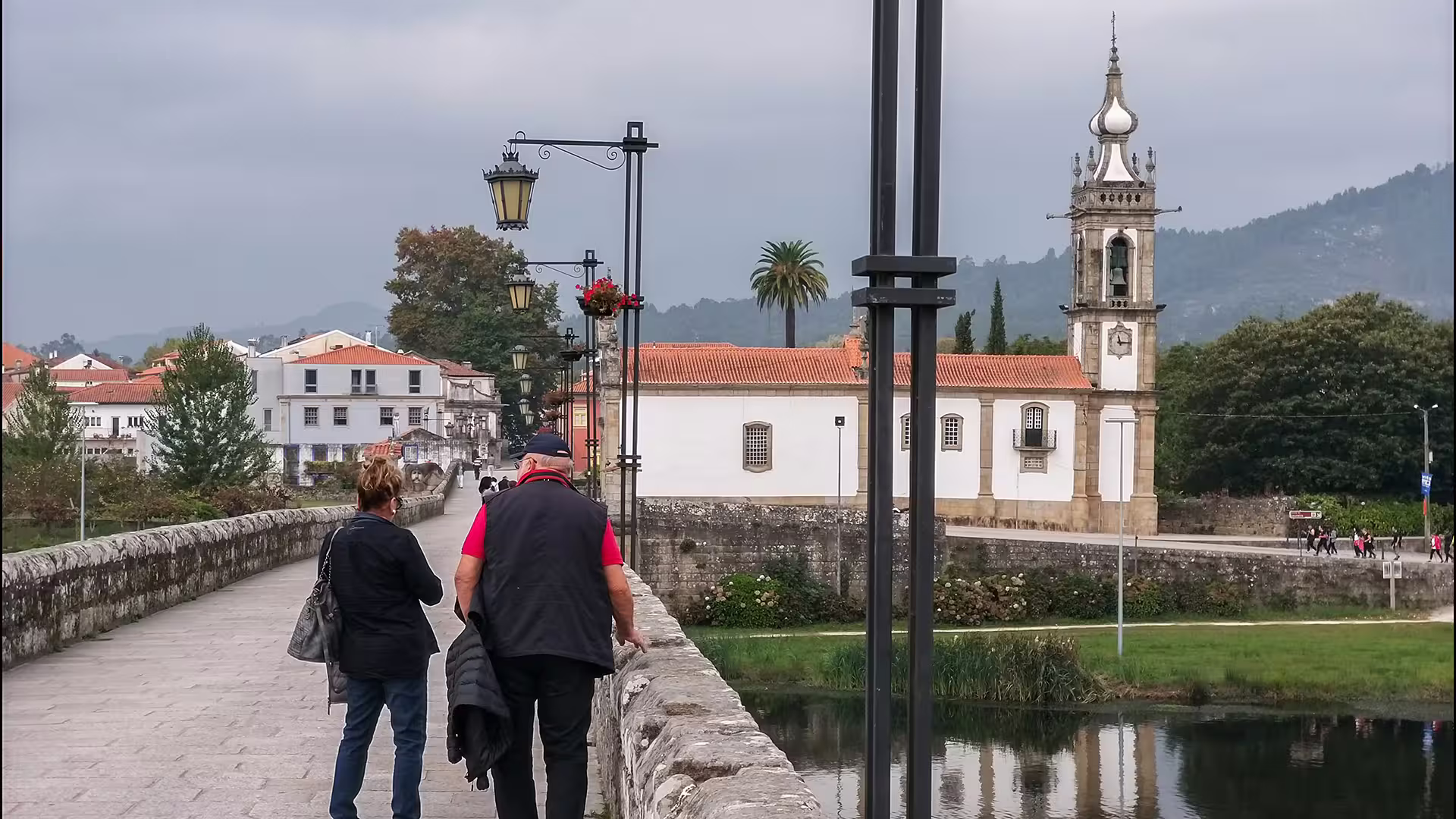 Tourists stroll across the historic bridge in Ponte de Lima with scenic views of the Vinho Verde region's lush landscape.
