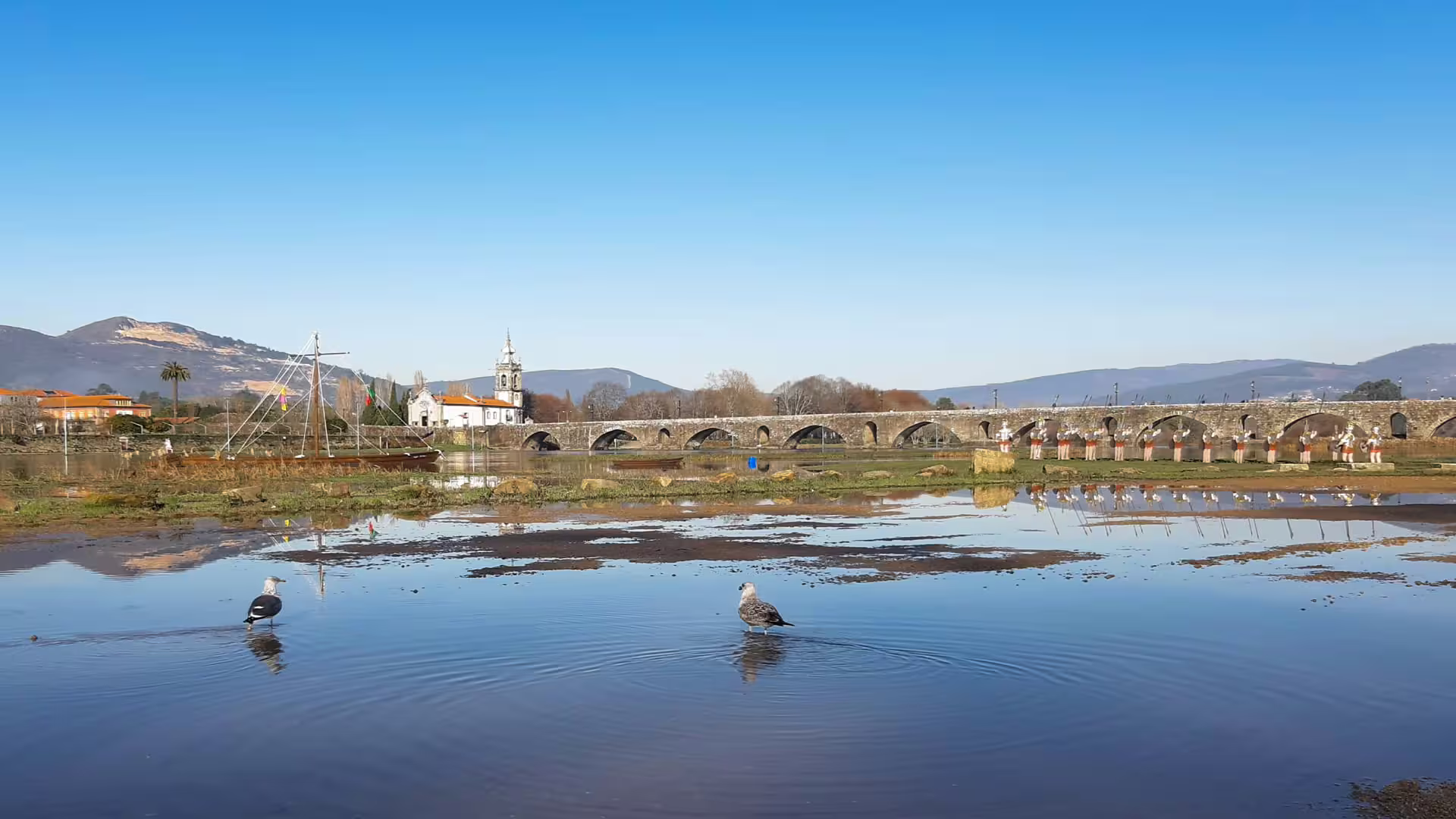 Historic stone bridge in scenic Ponte de Lima, Portugal, reflecting in the Lima River, ideal for Vinho Verde wine tours.