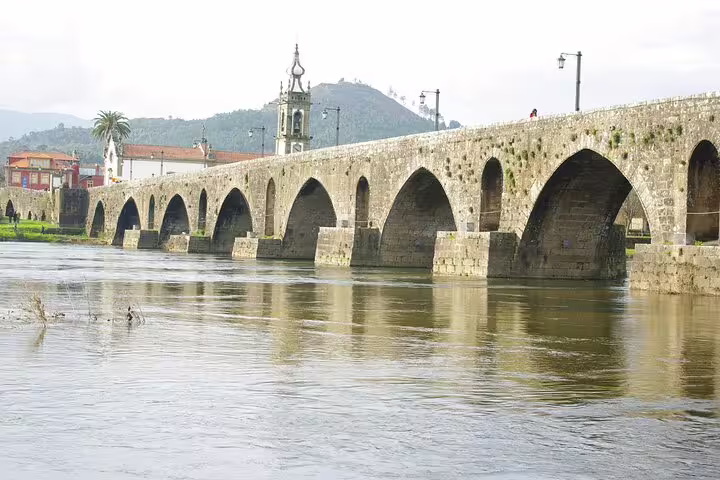 The historic Ponte de Lima stone bridge arches over the Lima River in a scenic Portuguese landscape.