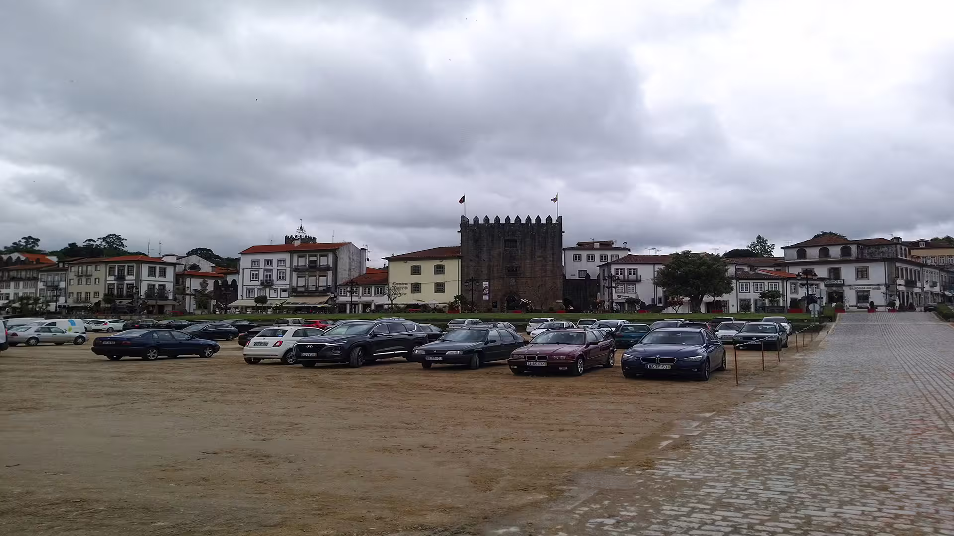 Scenic view of historic buildings and parked cars in Ponte de Lima, highlighting the charm of the Vinho Verde region on a cloudy day.