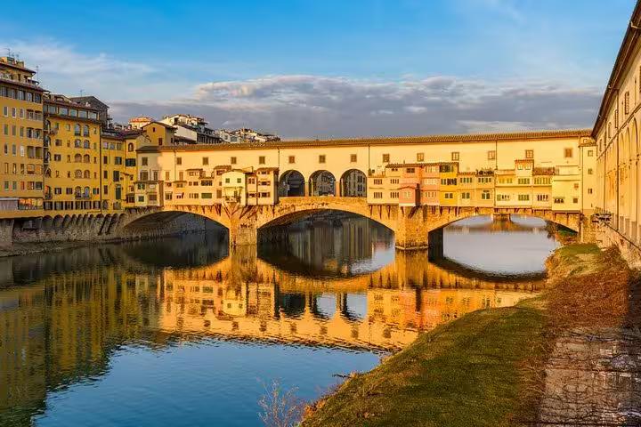 Scenic view of Ponte Vecchio reflecting on the Arno River at sunset during a Florence and Pisa day tour from Livorno.