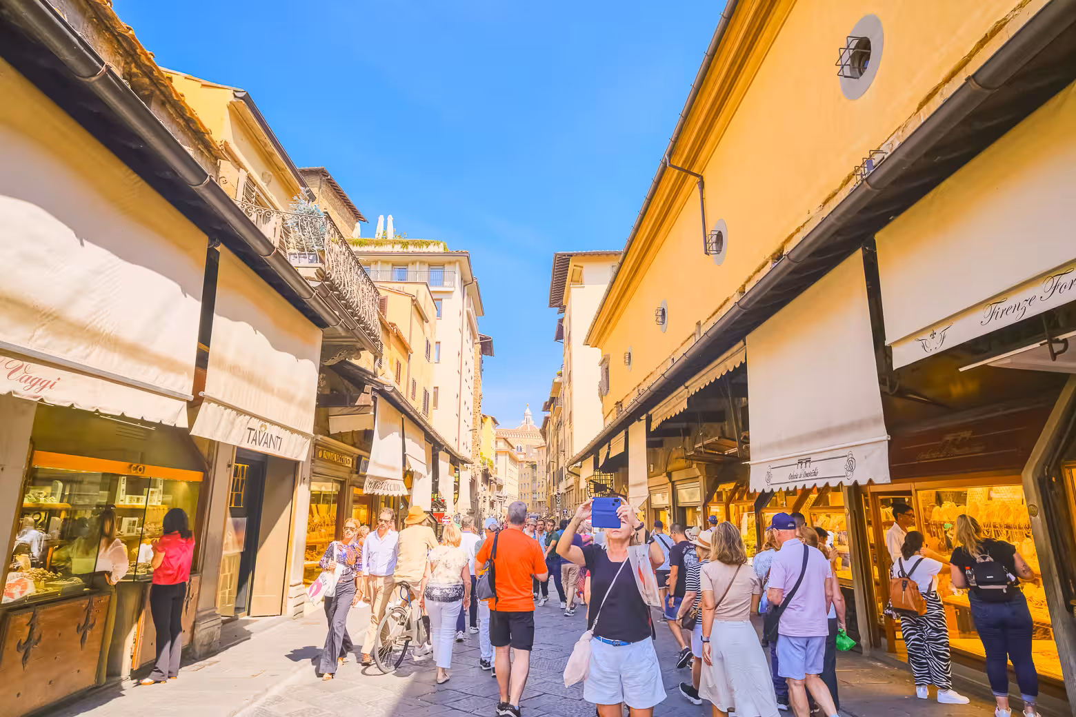 Tourists exploring the bustling shops on Ponte Vecchio in Florence during a full day excursion from Livorno.