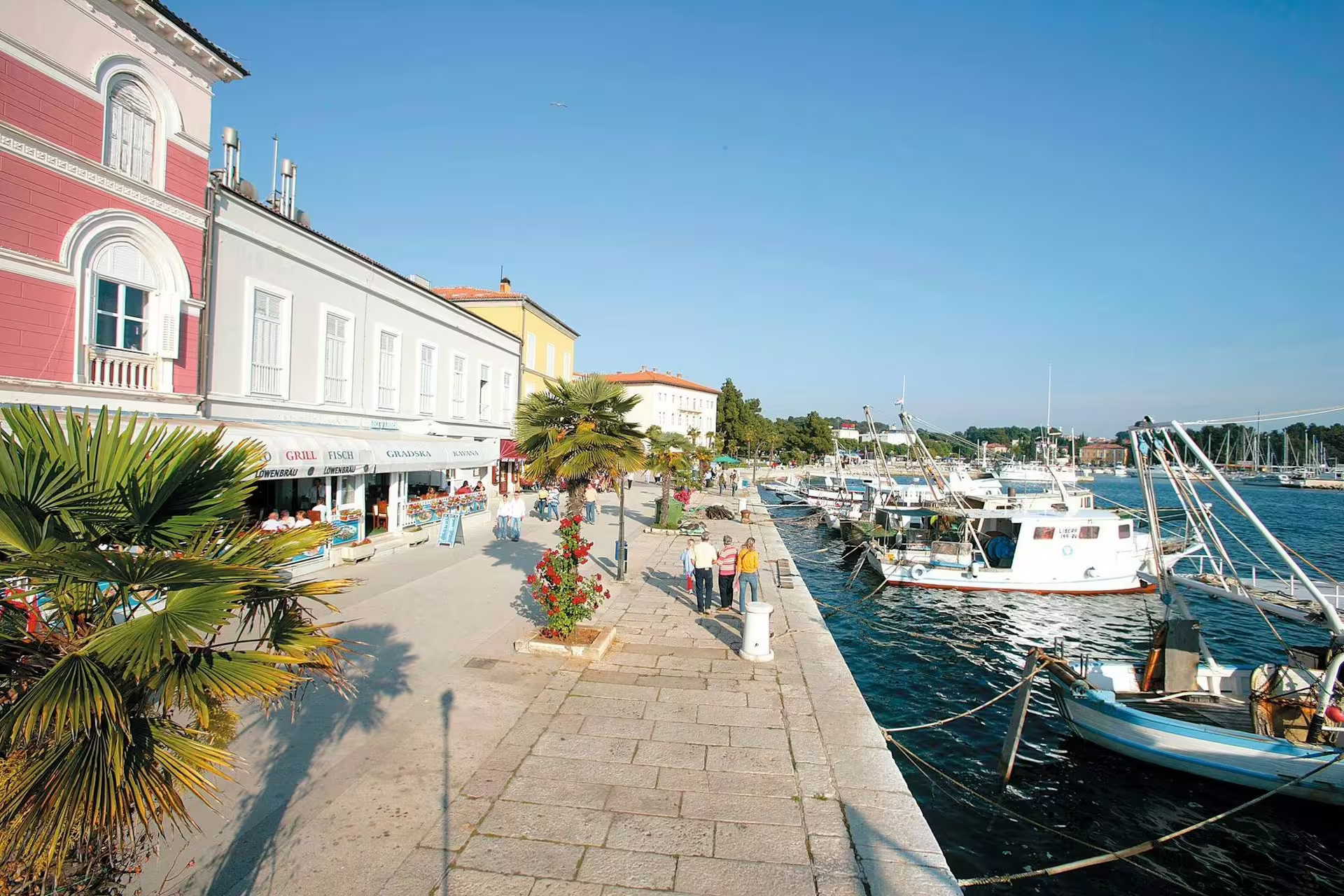 Poreč waterfront promenade with fishing boats and pastel buildings, scenic stop on Ancient Istria tour from Pula via Rovinj