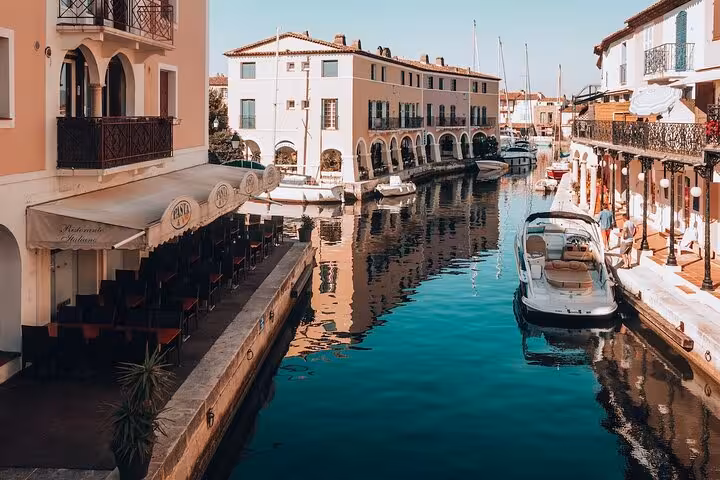 Charming canal scene in Port Grimaud with boats moored alongside picturesque buildings, ideal for a full day tour.