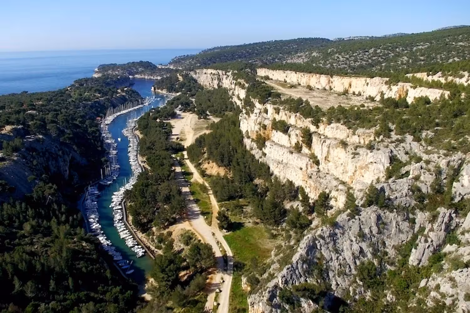 Aerial view of Port-Miou calanque with sailboats and limestone cliffs on En-Vau Port-Pin hiking tour