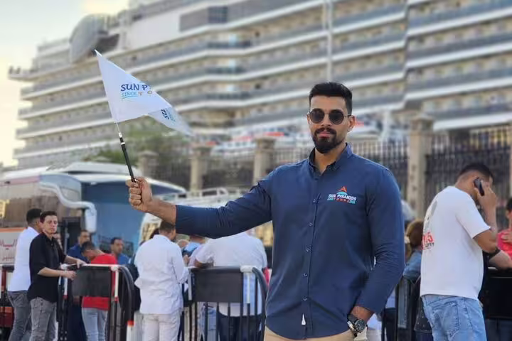 Tour guide at Port Said cruise terminal holding flag for Cairo day trip to Pyramids, Citadel and Khan el-Khalili