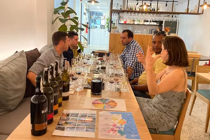 Small group enjoys sommelier-led Port wine tasting with five styles, aroma wheel, and Portugal map in a modern wine bar.