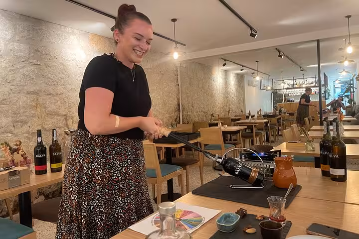 Guest tries the port tongs under a sommelier’s guidance during a 5 Port Wines tasting in Porto, Portugal, bottles ready.
