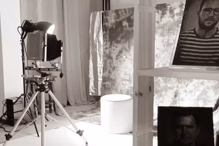Porto 19th-century metal portrait studio setup with large-format camera, lights, and tin-type prints on display