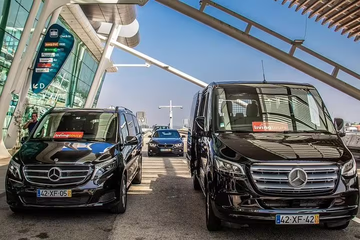 Luxury Mercedes vans ready for Porto private airport arrival transfer at the terminal entrance.