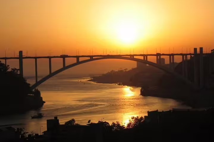 Stunning sunset view over Porto's Arrábida Bridge, casting a golden glow on the Douro River.