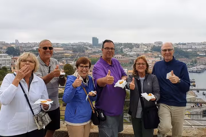 Small-group travelers enjoying local tastings with Porto city view on a half-day Porto & beach side tour experience