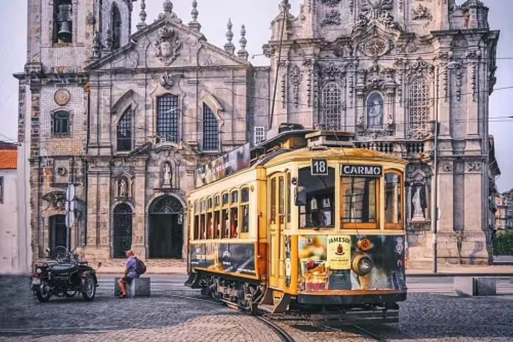 Historic yellow tram passing by the ornate Carmo Church facade in Porto, perfect for exploring the city on a private tuk tuk tour.