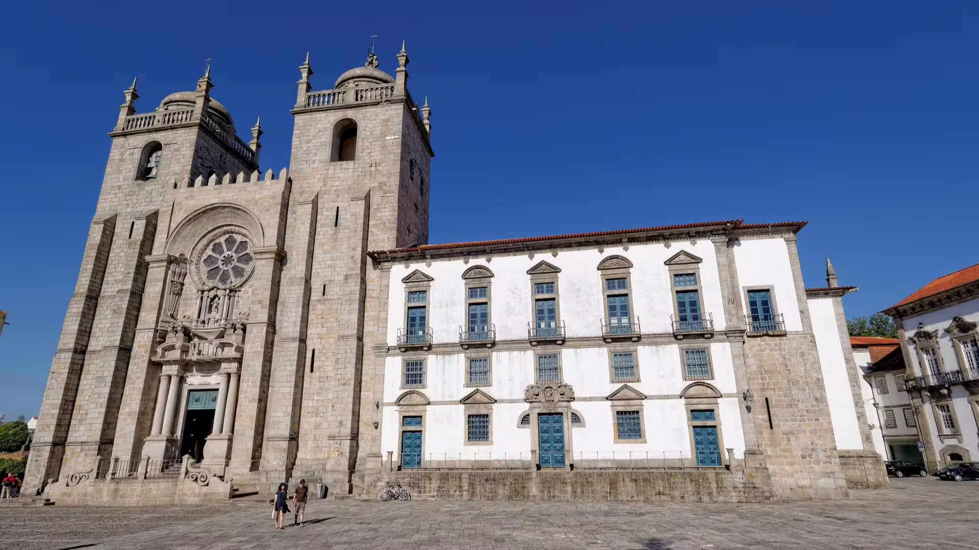 The majestic façade of Porto Cathedral and nearby architecture on a sunny day, highlighting cultural tour appeal.