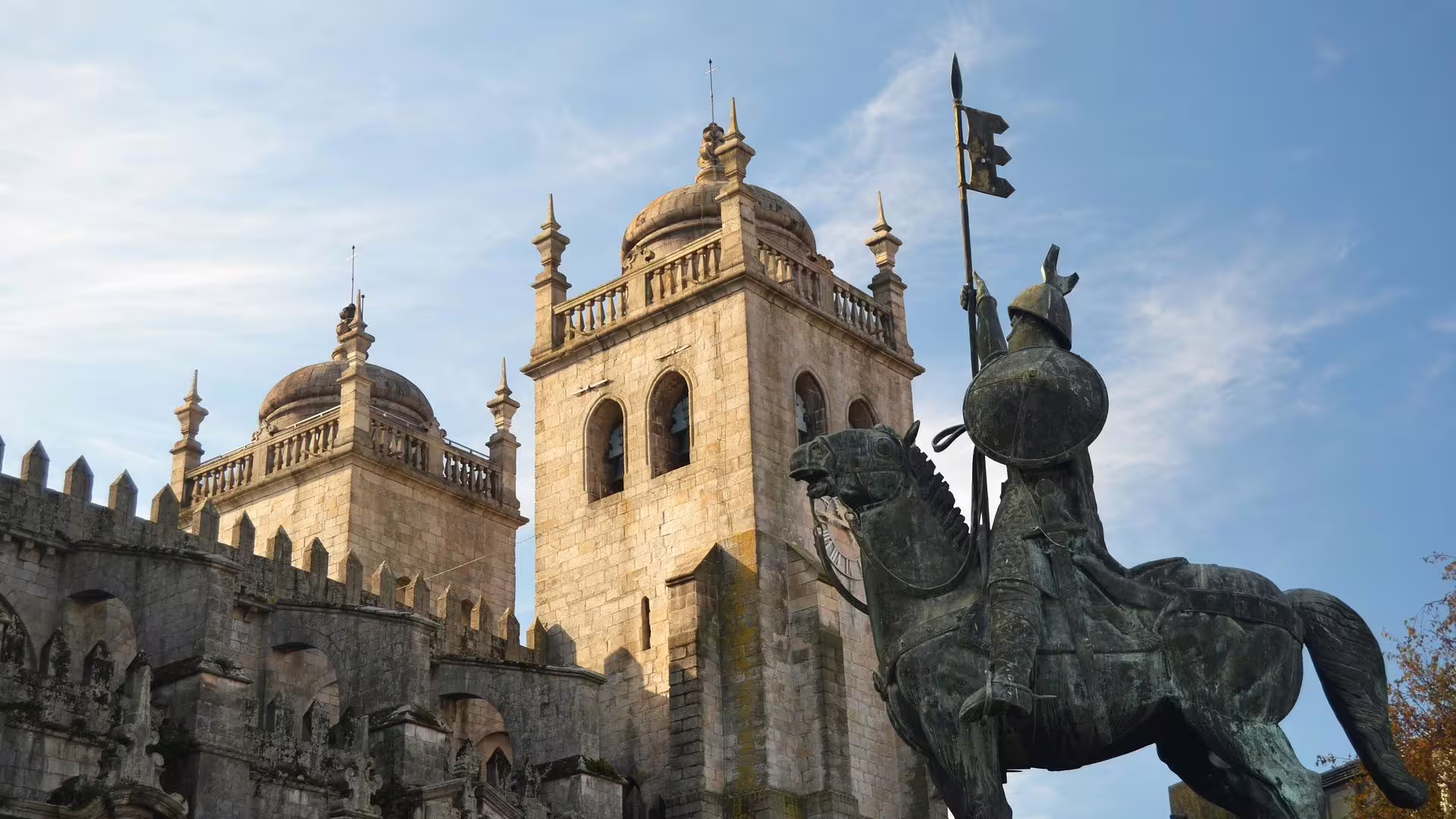 Impressive medieval statue and Porto Cathedral towers under a clear sky, perfect for an enriching city tour.