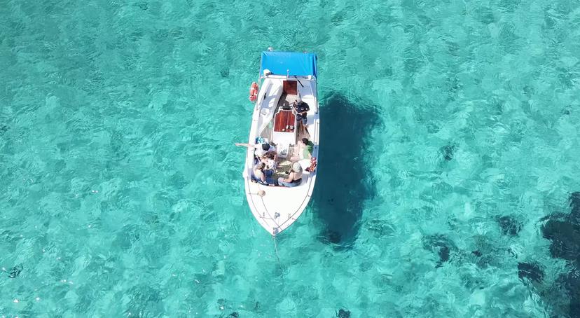Aerial view of a boat in crystal-clear turquoise waters near Porto Cervo, perfect for a scenic Golfo Aranci tour.