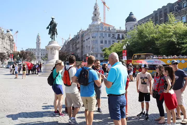 Tour group exploring Porto's iconic Avenida dos Aliados with historic architecture and statues in the background.
