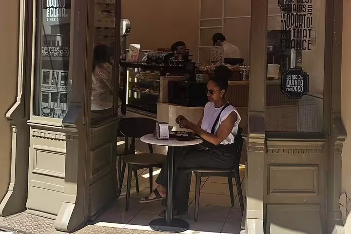Woman enjoying a coffee at a charming Porto café, perfect for a private city tour with seafood lunch and coastal views.
