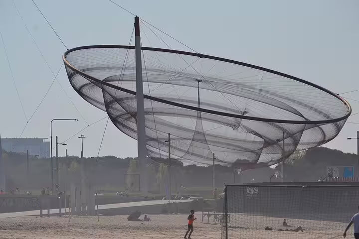 Iconic seaside sculpture in Porto with beachgoers enjoying the sunny coastal views on a private city tour.