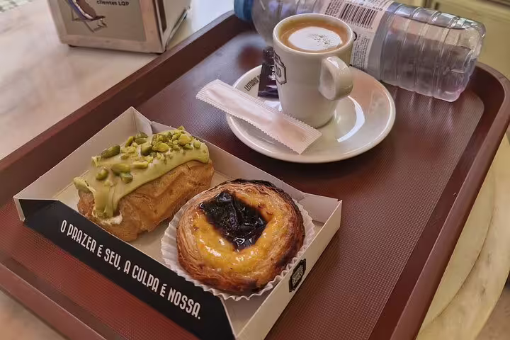 Enjoy a classic Portuguese coffee with a pastel de nata and pistachio éclair during your Porto city tour.