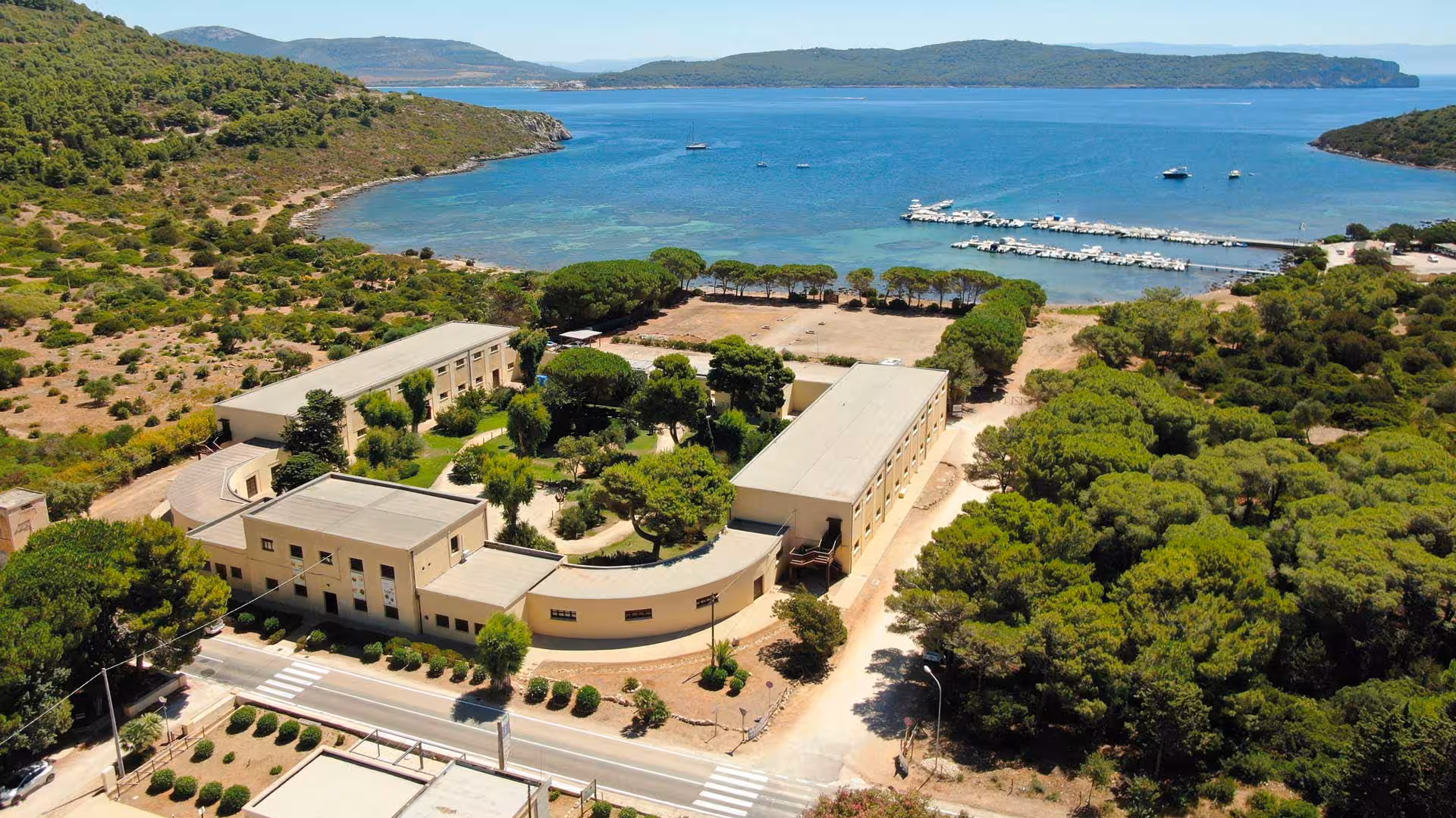 Aerial view of Porto Conte Park Ecomuseum in Alghero, showcasing lush greenery and nearby coastline.