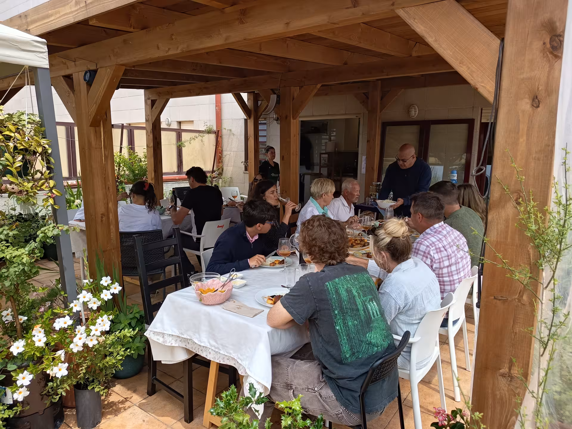 Guests enjoy a communal meal under a wooden pergola, savoring dishes from the Porto cooking class with Jorge and Isabel.
