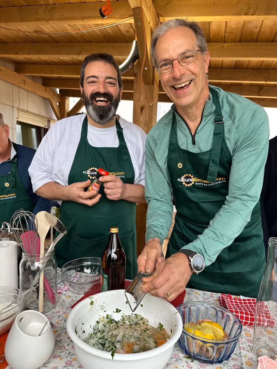 Smiling guests in Porto cooking class with Isabel, grating ingredients for a flavorful Portuguese dish.
