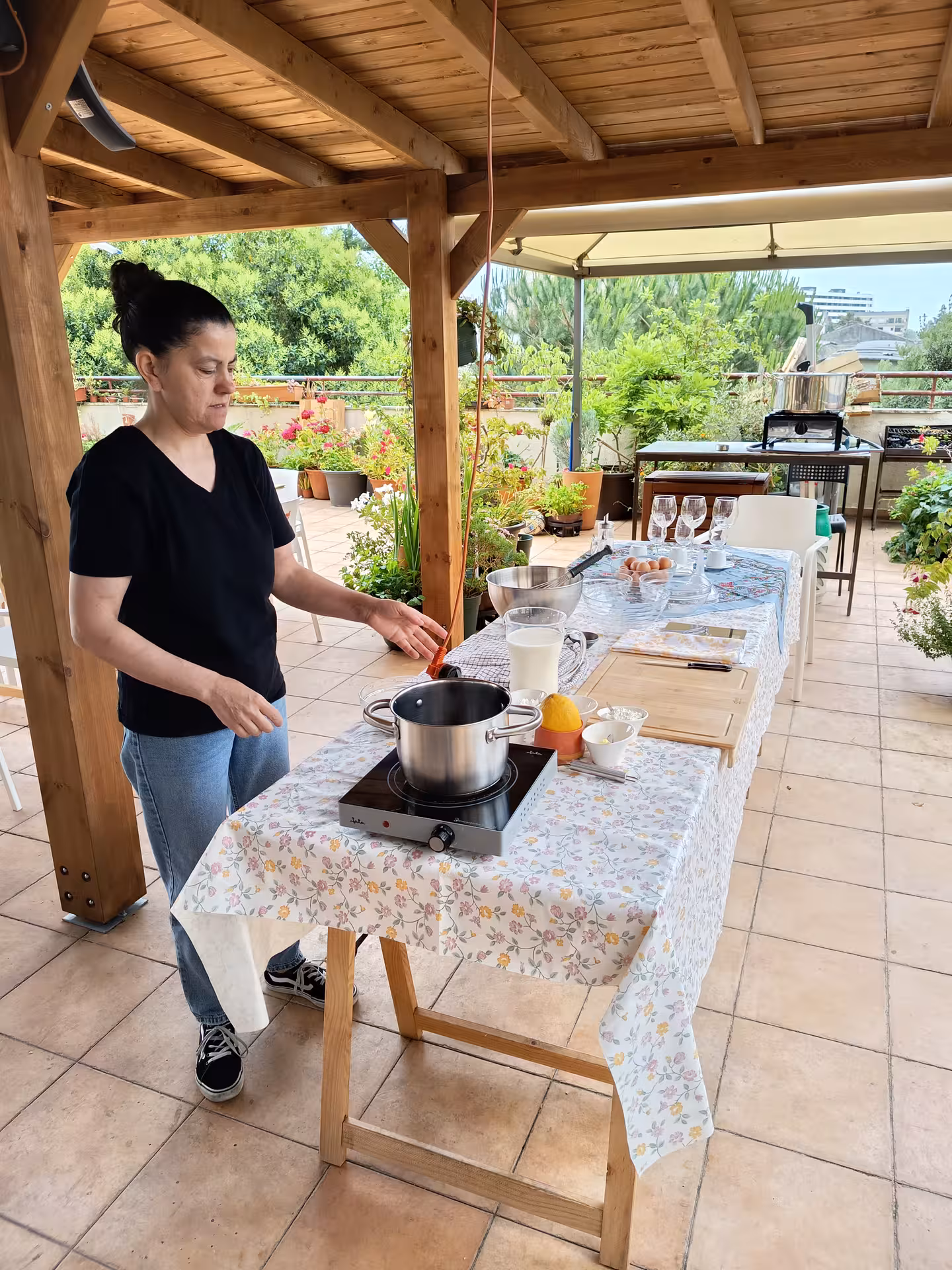 Isabel prepares ingredients for a Portuguese dish on a sunny terrace during a Porto cooking class.