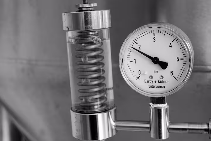 Close-up of a pressure gauge and metal coil at a Porto craft brewery, showcasing brewing equipment and technology.