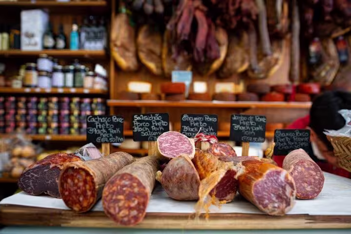 Variety of cured meats and sausages on display at a Porto market, perfect for a Portuguese culinary exploration.