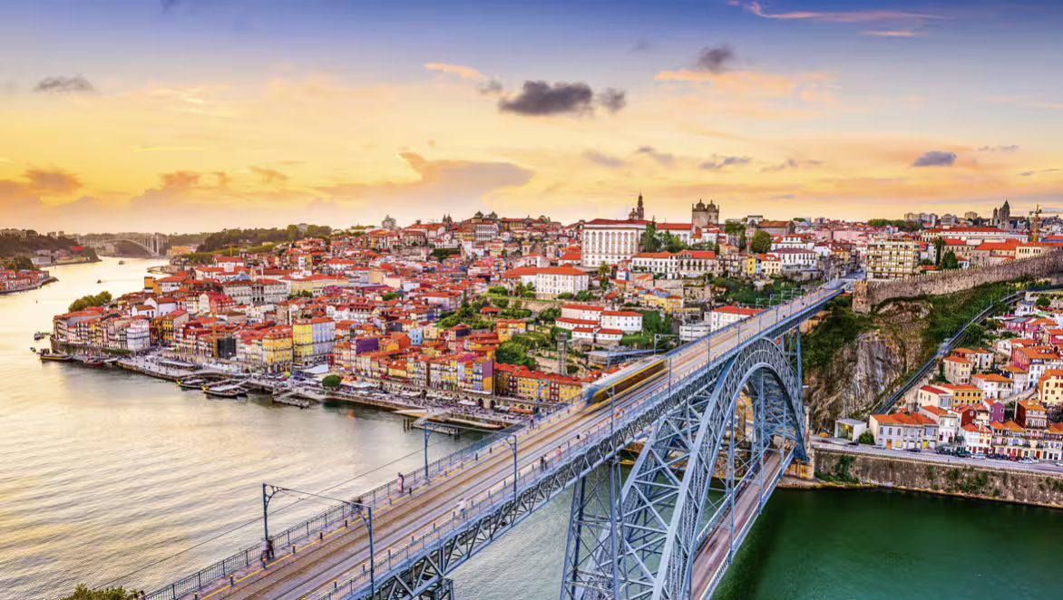 Sunset view of Porto with the iconic Dom Luís I Bridge spanning the Douro River, perfect for a day trip from Lisbon.