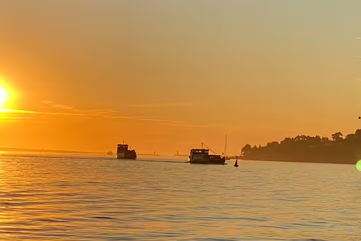 Scenic Douro River boat tour at sunset in Porto with included wine and snacks, highlighting serene water and vibrant sky.