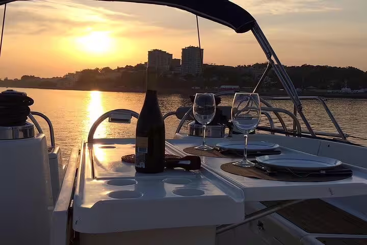 Sunset view from a Douro River boat tour in Porto featuring a table set with wine and snacks for an unforgettable experience.