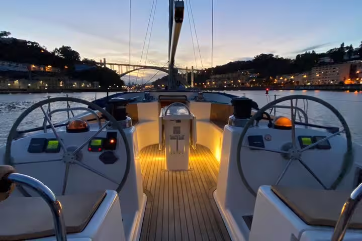 Scenic Douro River boat tour at sunset in Porto with illuminated deck, offering wine and snacks for a memorable experience.