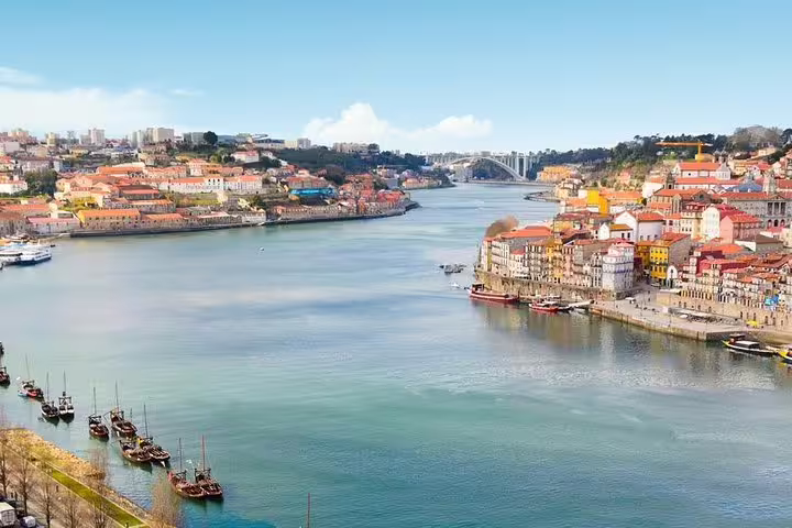 Panoramic view of Porto's colorful riverside architecture lining the Douro River with boats and bridges.