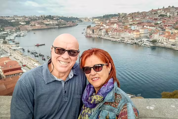 Couple enjoying scenic views of Porto's Douro River on a private day trip from Lisbon, showcasing vibrant cityscape and waterfront.