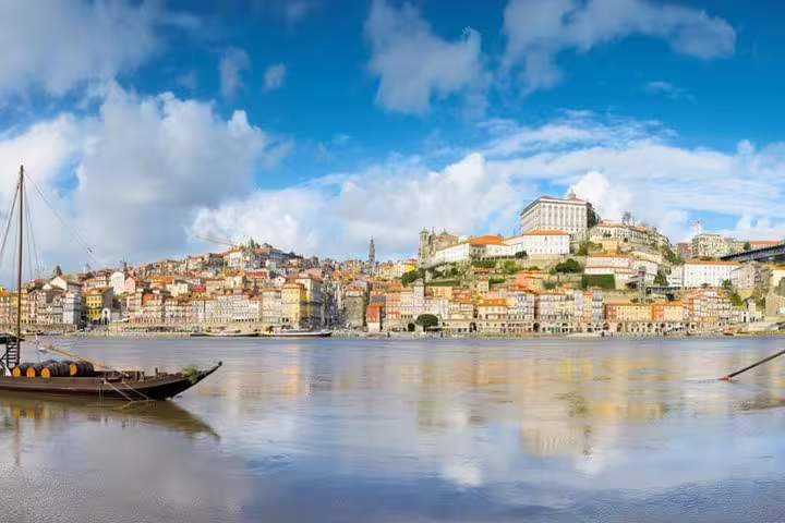 Panoramic view of Porto's colorful riverside with traditional Rabelo boat on Douro River, perfect for private Porto and Aveiro tours.