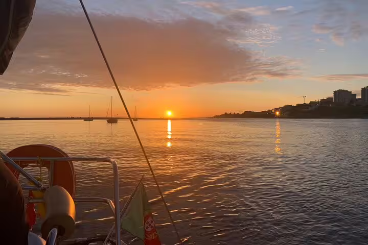 Sunset view from a boat on the Douro River in Porto, with calm waters reflecting the sky, perfect for a wine and snack tour.