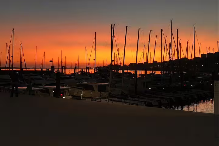 Sunset over Porto marina with sailboats silhouetted, ideal for Douro River boat tour featuring wine and snacks experience.