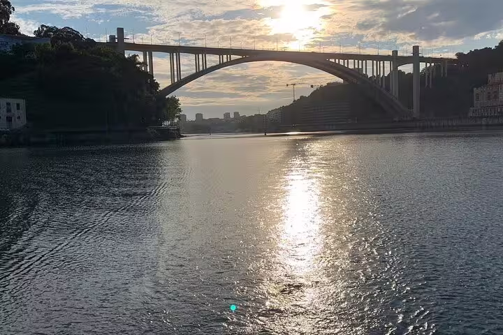 Scenic view of sunset over the Douro River in Porto with iconic bridge, perfect for a relaxing boat tour with wine and snacks.
