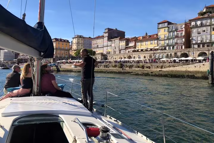 Passengers admire Porto's vibrant riverside buildings during a private sail on the Douro River at sunset.