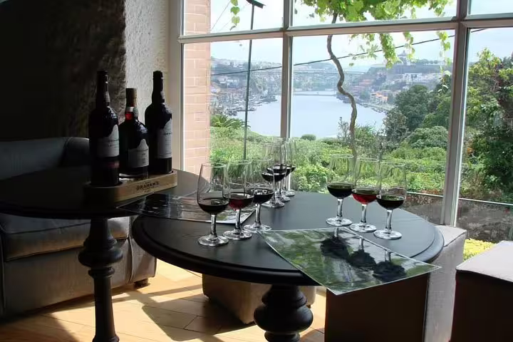 Scenic view of Douro River from a Porto winery, with wine bottles and glasses set for tasting on a table.