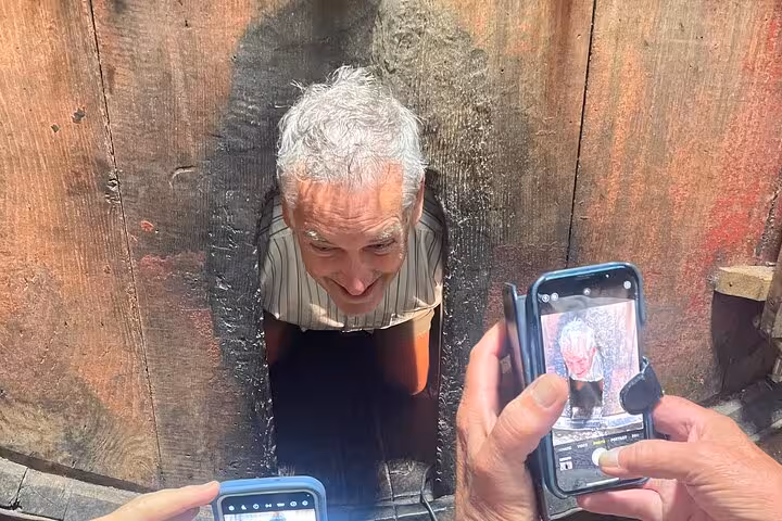 Guest peeks from a port wine barrel as others snap photos during a sommelier-led cellar tour in the Douro Valley near Porto.