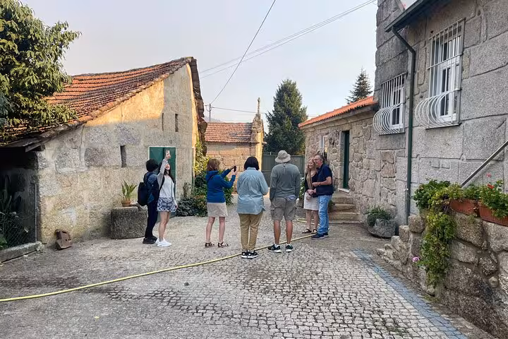 Small group with sommelier in a rustic stone village courtyard on a Porto Douro Valley wine tour with lunch and boat trip.
