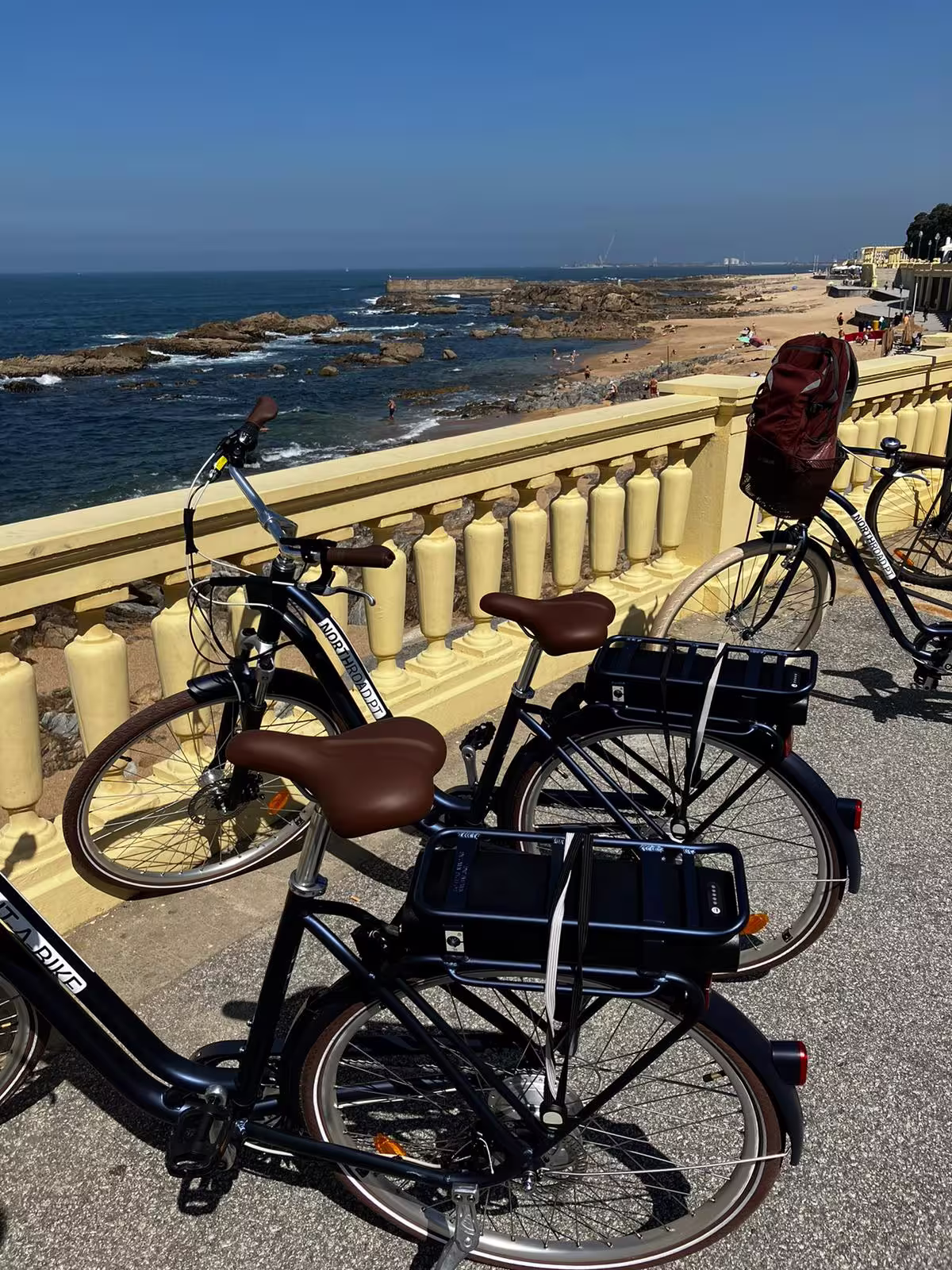 E-bikes parked along Porto's scenic coastline, offering stunning ocean views and a glimpse of sandy beaches on the tour.