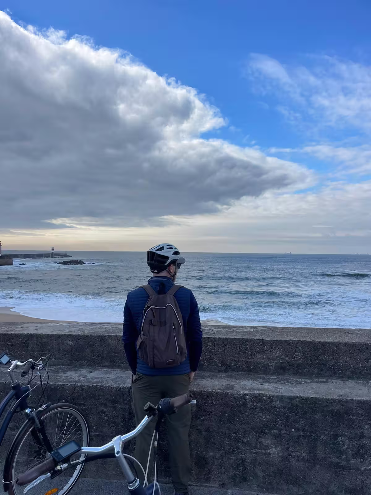 Solo traveler admires the ocean from a seaside path on a Porto E-bike Tour & Seafood Tasting adventure.