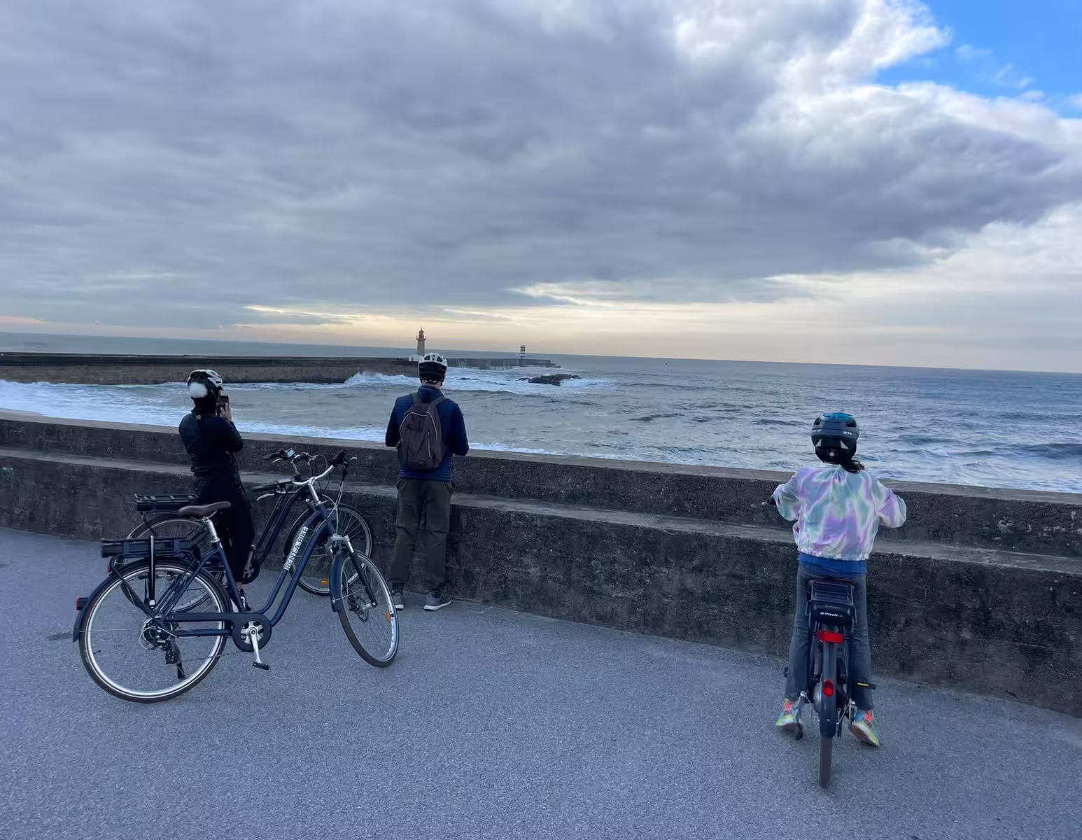 Tourists on e-bikes enjoy scenic ocean views during Porto E-bike Tour & Seafood Tasting experience.