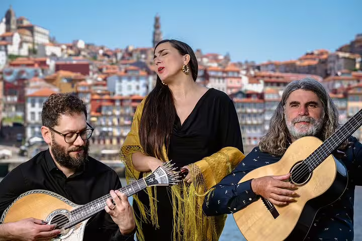 Musicians perform traditional Fado music by Porto's scenic riverfront, with colorful historic buildings in the background.