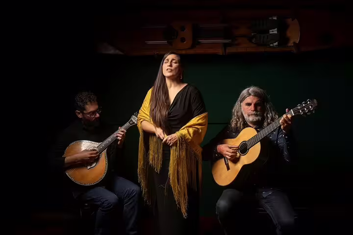 Trio performing traditional Fado music in Porto, featuring passionate vocals and guitarists, capturing the city's riverfront ambiance.