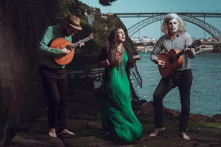 Musicians perform traditional Fado by Porto's scenic riverfront, with iconic bridge background, creating an authentic cultural experience.